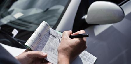 Un agente pone una multa de tráfico por mal estacionamiento