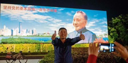 Un joven chino posa ante una valla propagandística con la imagen del difunto Deng Xiaoping en vísperas del 40.º aniversario de la política de “reforma y apertura” del país en Shenzhen,