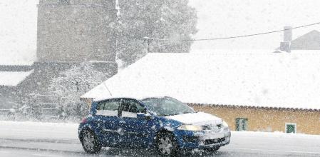 Un vehículo circula por la localidad leonesa de Pandorado, cubierta de nieve a causa del temporal que afecta al norte de la provincia castellanoleonesa.