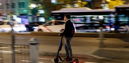 Un joven se deplaza en patinete eléctrico por Madrid 