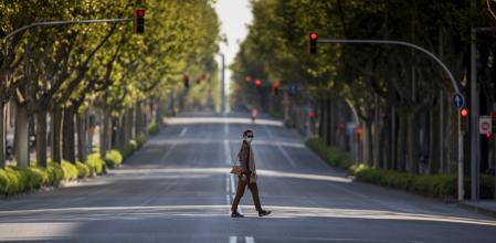FOTO: MANÉ ESPINOSA. EFECTOS CORONAVIRUS DURANTE EL DECRETO DEL ESTADO DE ALARMA. IMAGEN DE LA AVENIDA DIAGONAL EL DOMINGO DE RAMOS PRACTICAMENTE VACIA. UNA MUJER CRUZANDO LA AVENIDA PROTEGIDA CON MASCARILLA