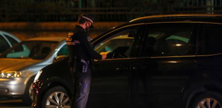 Un policía local de Sevilla controla que un ciudadano está realizando un desplazamiento permitido durante el horario de toque de queda&nbsp;