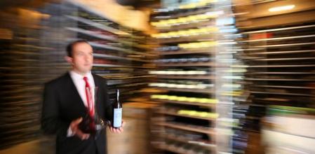 Un sommelier retirando un vino de la bodega de un restaurante