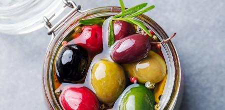 Olives assortment in glass jar with oil. Top view. Close up