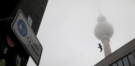 Un cartel informa a los peatones que usen una mascarilla protectora cerca de la torre de televisión Berliner Fernsehturm en Berlín