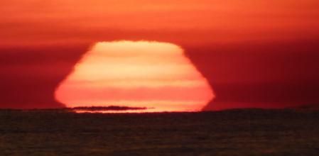 Sol deformado frente a la costa de Barcelona, captado desde la playa de Gavà.