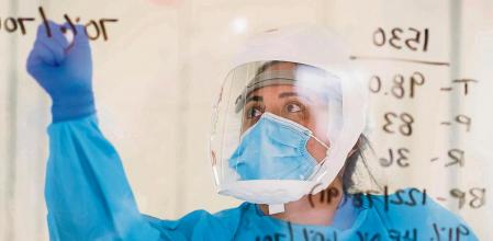 A nurse writes information on the window of a patient's room at the Covid-19 Intensive Care Unit (ICU) of Salinas Valley Memorial Hospital in Salinas, California, U.S., on Tuesday, Jan. 26, 2021. California had coronavirus case average numbers drop by more than a third in the course of a week. Such improvements inspired California Governor Gavin Newsom to ease social-distancing measures earlier this week. Photographer: Nic Coury/Bloomberg