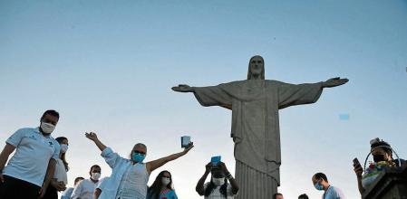 TOPSHOT - Therezinha da Conceicao, 80, and Dulcineia da Silva, 59, show their vaccination cards after they were inoculated with the Sinovac Biotech's CoronaVac vaccine against COVID-19 coronavirus next to Rio de Janeiro's interim Governor Claudio Castro (L) and Rio de Janeiro's Mayor Eduardo Paes (4-R), at the Christ The Redeemer statue, on the Corcovado mountain in Rio de Janeiro, Brazil on January 18, 2021. (Photo by MAURO PIMENTEL / MAURO PIMENTEL / AFP)