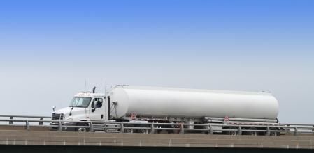 A semi fuel tanker truck hauling a load of gasoline/petrol to local retail gas stations. Shot on an overpass interchange with copy space.