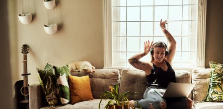 Shot of a young woman using a laptop and headphones on the sofa at home