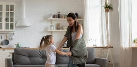 Overjoyed young mom or nanny have fun playing with cute little preschooler girl child, excited mother dancing with small daughter, enjoying funny childish activity with excited kid on weekend at home