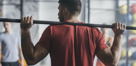 Back view of a sportsman lifting weights at the gym.