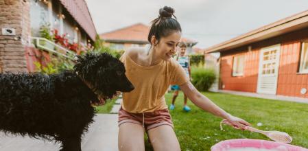 Photo of mother and son bathing their dog in the yard