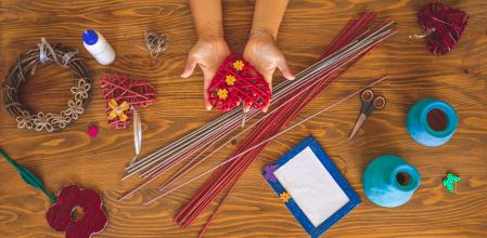 Woman hands holding red paper heart and creating paper art top view