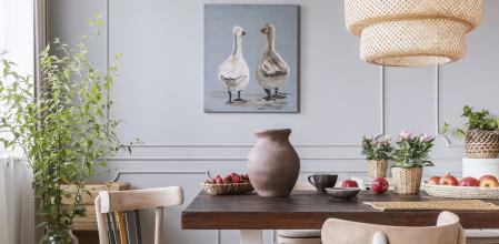 Wooden chairs at table with flowers in natural dining room interior with poster and lamp. Real photo