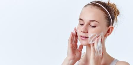 Chica limpiándose el rostro con un limpiador facial