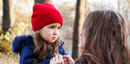 Scared daughter holding mother's hands in autumn park. Child girl express sad emotions, complain about their own problems