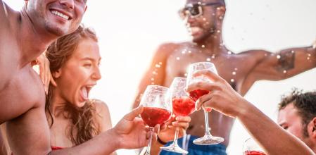 Happy friends drinking sangria wine at exclusive boat party - Young people having fun in summer vacation - Focus on left man hand glass - Travel, friendship, holidays and youth lifestyle concept