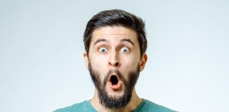 Man with shocked, amazed expression isolated on gray background