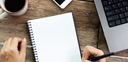 Top view Female hand is writing blank paper and computer on old wooden table