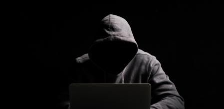 Hacker working on laptop in the dark