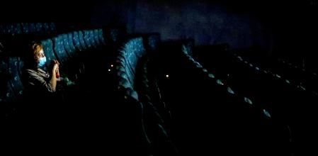 Un espectador con mascarilla en una sala de cine desierta en Barcelona