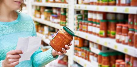 Una mujer leyendo la etiqueta de una salsa de tomate