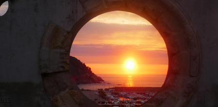 Tras un ventanal circular, el amanecer en Palamós.