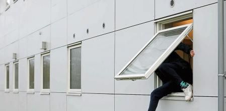 FILE PHOTO: A resident climbs through a window at Kaershovedgaard, a former prison and now a departure centre for rejected asylum seekers in Jutland, Denmark, March 26, 2019. REUTERS/Andrew Kelly/File Photo