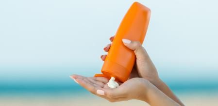 Woman hand apply sunscreen on the beach