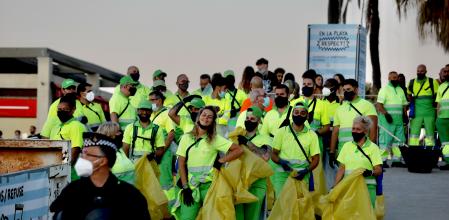 Un agente de la Guardia Urbana precede un grupo de trabajadores de Barcelona Neta