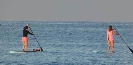 Dos mujeres haciendo padle surf en la playa de Gavá.