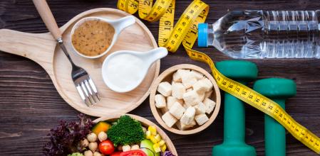 Fresh vegetable salad and healthy food for sport equipment for women diet slimming with measure tap for weight loss on wood background. Healthy Sport Concept