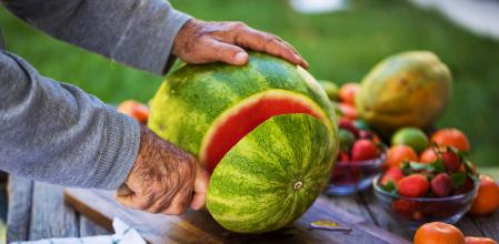 Un hombre cortando una sandía