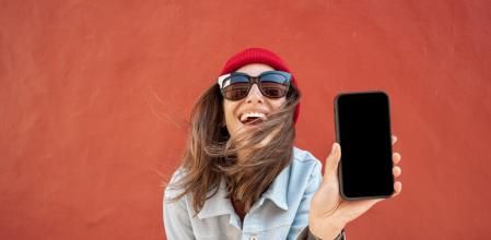 Una joven sonríe con el móvil en la mano