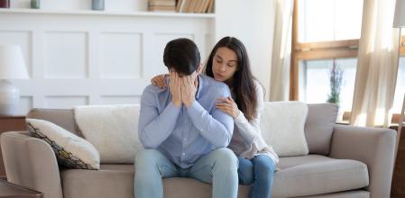 Loving young woman touch embrace comfort upset husband feeling distressed mourning or yearning at home, millennial wife make peace reconcile with man after cheating, couple have relationship problems