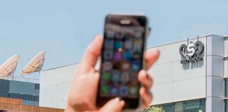 (FILES) In this file photo taken on August 28, 2016, a woman uses her iPhone in front of the building housing the Israeli NSO group 