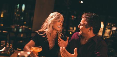 Mature man and woman having fun and laughing together on date night at luxurious bar