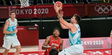 Slovenia's Luka Doncic (C) past Japan's Daiki Tanaka (front L) in the men's preliminary round group C basketball match between Slovenia and Japan during the Tokyo 2020 Olympic Games at the Saitama Super Arena in Saitama on July 29, 2021. (Photo by Aris MESSINIS / AFP)