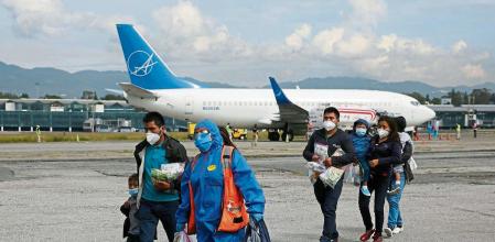 A government employee walks along families deported from the U.S. under Title 42 as part of the efforts of the U.S. government to expedite removals of some families to dissuade record numbers of migrants from making the journey north, at the La Aurora International airport in Guatemala City, Guatemala August 4, 2021. REUTERS/Luis Echeverria