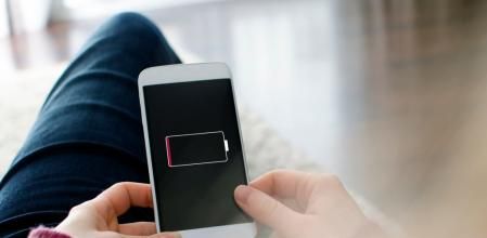 A woman is holding a mobile phone in her hands. On the device screen of the smart phone  visible is an empty battery. The photo was taken over the model's shoulder. I have created the battery icon in adobe illustrator myself. It is intended to look like a generic battery icon