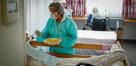 FOTO ALEX GARCIA UNA AUXILIAR DA DE COMER A UNA RESIDENTE EN EL GERIATRICO LOS TILOS. ESTADO DE ALARMA Y CONFINAMIENTO POR EL CORONAVIRUS 2020/04/19