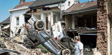 FILE - In this file photo dated Monday, July 19, 2021, a woman looks at cars and homes damaged after torrential rain caused flooding in Liege, Belgium. A new massive United Nations science report is scheduled for release Monday Aug. 9, 2021, reporting on the impact of global warming due to humans. (AP Photo/Valentin Bianchi, FILE)