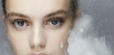 portrait of a beautiful woman behind a frozen window - professionel make-up , grey background