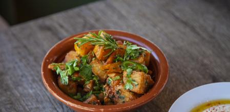 Lebanese Spicy Potatoes Dish over wooden restaurant table | Batata Harra