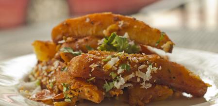Spicy fried Indian potato wedges with coriander and coconut shavings