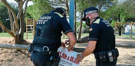 Dos agentes de la Policia Local de Palafrugell colocan un cartel de cierre nocturno del paraje Xirlo donde se concentran jovenes para hacer botellon y saltarse el toque de queda nocturno. Paco Dalmau/ NORD MEDIA