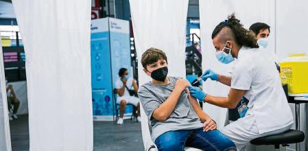 foto XAVIER CERVERA 04/08/2021 Guillem i Adrià Martinez Vidal, hermanos gemelos de 12 años, acompañados por su madre Carla Vidal (ha dado permiso d publicación imágenes), se vacunan contra la covid en la fira Montjuïc, Barcelona, el primer dia q se permite a menores entre 12 y 15 años (el ICS ha montado esta foto, situación, para la prensa gráfica)