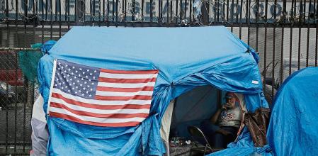 FILE - A man smokes inside a tent on skid row Friday, March 20, 2020, in Los Angeles. Auditors said Tuesday, Aug. 24, 2021, a California agency didn't properly distribute federal funds meant to help homeless residents during the coronavirus pandemic and the mismanagement was so prolonged the state may lose the money because of missed deadlines. (AP Photo/Marcio Jose Sanchez, File)