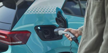 Un conductor enchufa su coche a la red eléctrica para cargar la batería&nbsp;